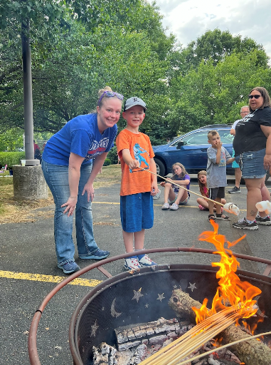 Family roasting a marshmallow over a fire pit